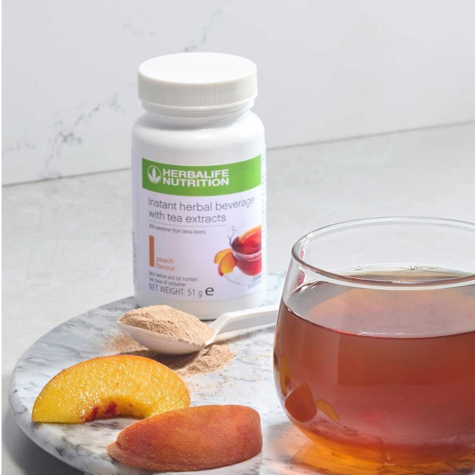 Herbalife Instant Herbal Beverage with Tea Extracts Peach Flavour 51g served with prepared tea, peach slices and powder